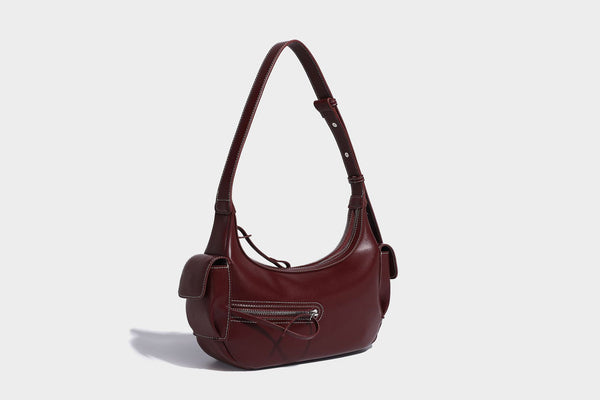 Smooth leather-look crescent shoulder bag with front zip pocket, side flap pockets, adjustable strap, and silver-tone, detail