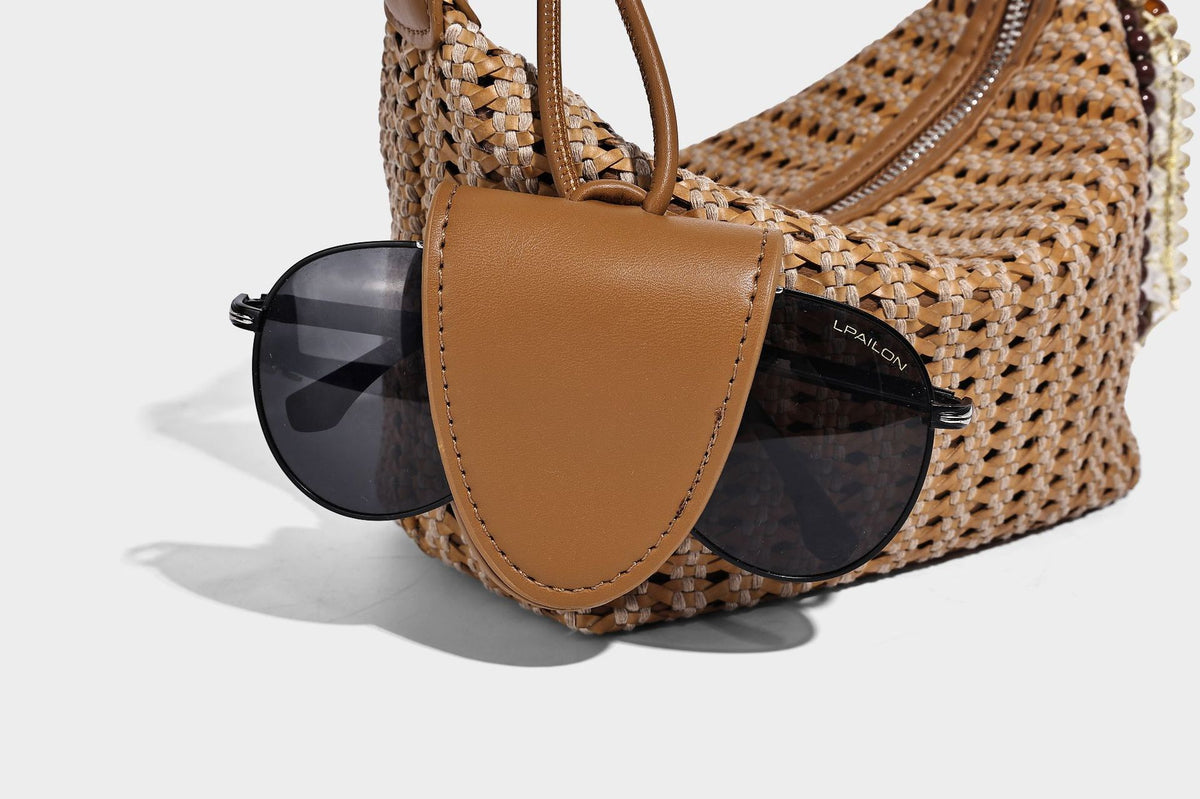 Woven crescent shoulder bag with leather-look knotted handle, zip top, attached mini pouch, and silver-tone hardware, detail