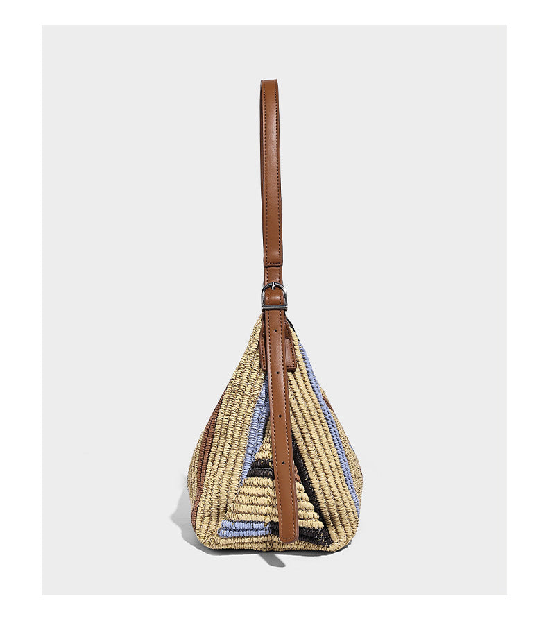 Slouchy woven straw hobo shoulder bag with beige, black, brown, and blue vertical stripes and brown leather-look trim, detail