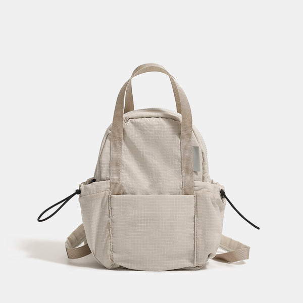 Small rounded mini backpack handbag in matte ripstop-texture fabric with top webbing handle, front pocket, side drawstring