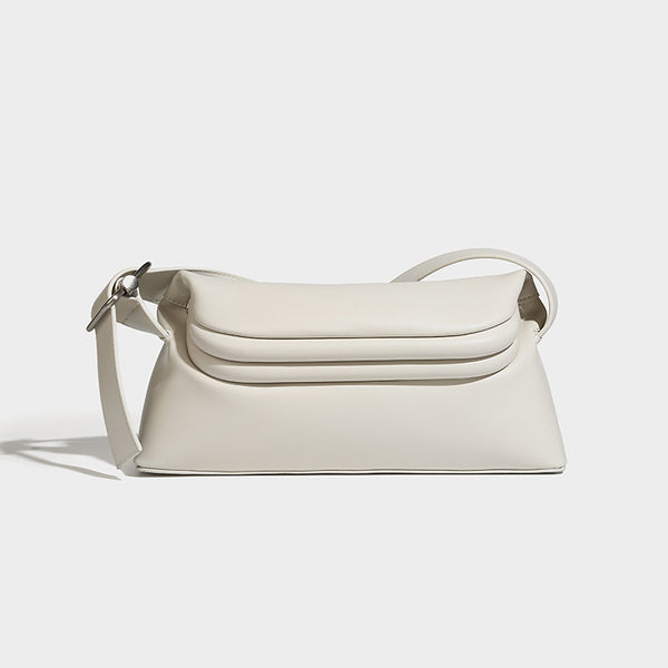 Compact structured baguette shoulder bag with smooth leather-look finish, zip top, and adjustable silver-buckle strap, detail