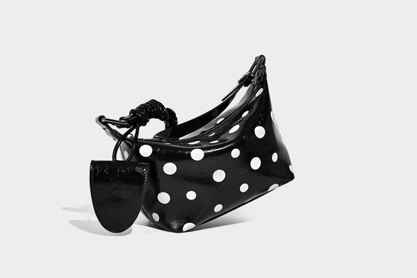 Kompakte glänzende Hobo-Schultertasche in Schwarz mit weißen Punkten, Reißverschluss, Beschlägen in Gunmetal und befestigtem Überschlag vorne