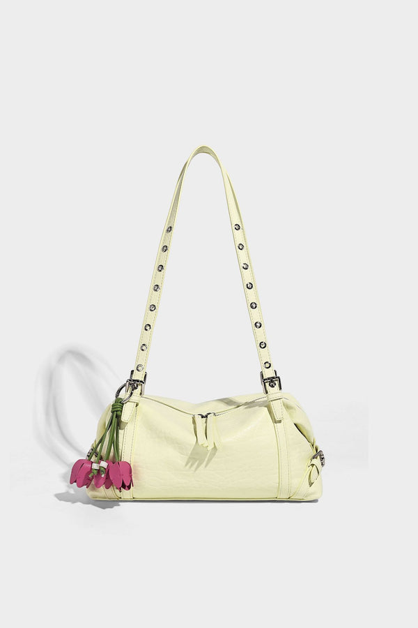 Pale yellow leather-look barrel bag with silver grommet-studded shoulder straps, top zip closure, and pink tulip floral