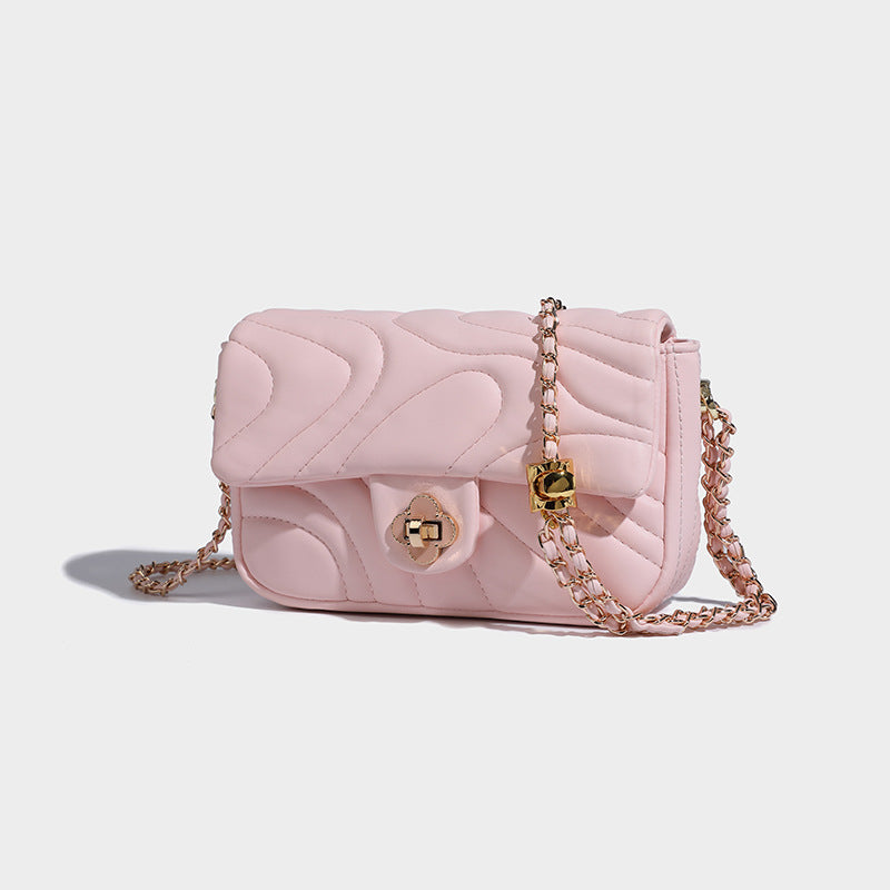 Compact cream quilted flap crossbody bag with wave stitching, gold-tone chain strap, and four-petal turn-lock clasp, detail