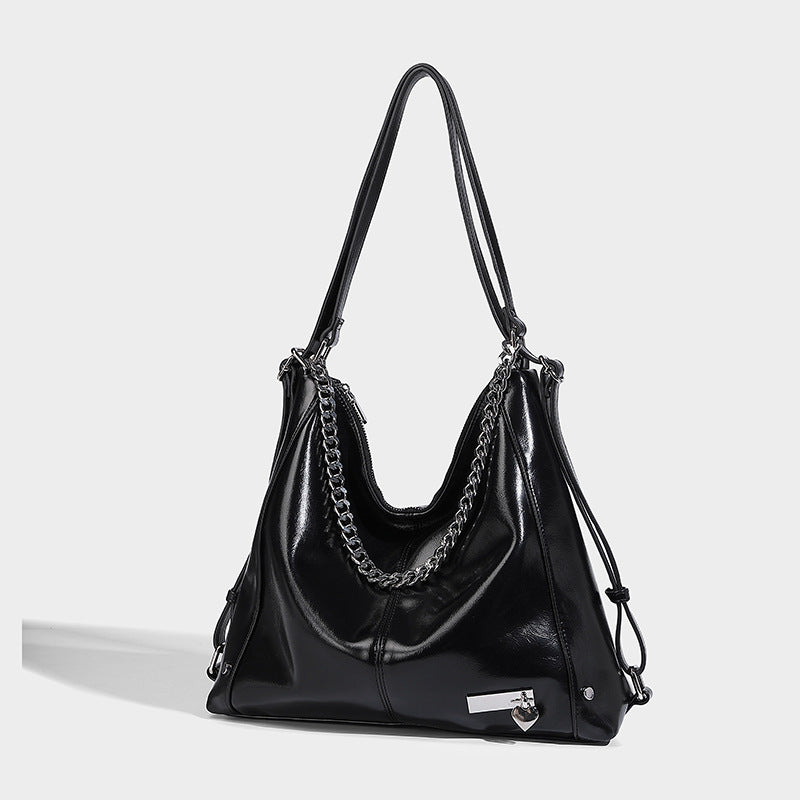 Glossy black slouchy hobo tote bag with silver-tone chain accent, top zip closure, and long shoulder straps, front view