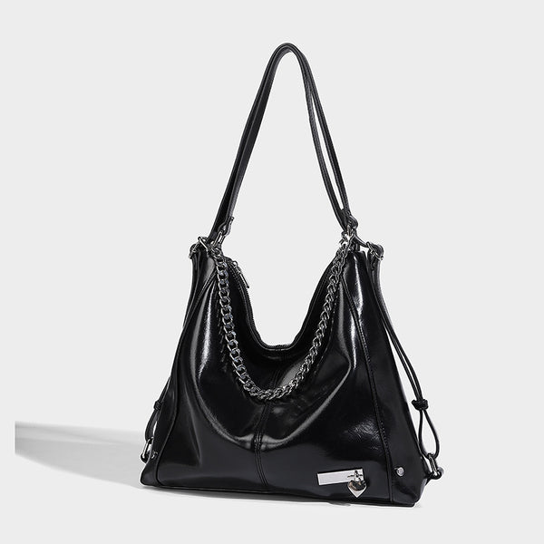 Glänzend schwarze, weich fallende Hobo-Tote-Bag mit silberfarbenem Kettenelement, Reißverschluss oben und langen Schulterriemen, Vorderansicht