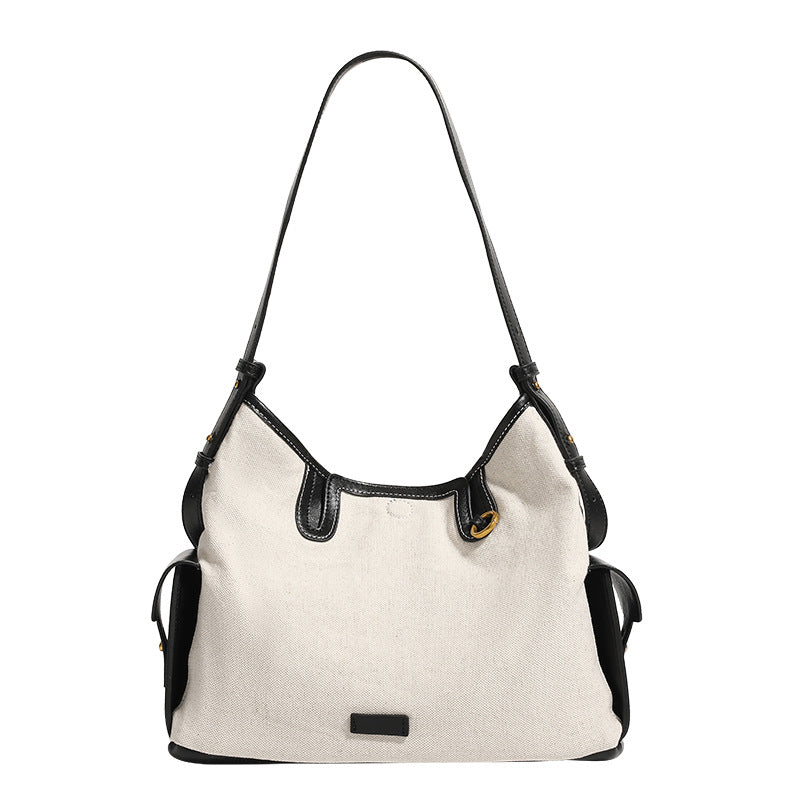 Off-white canvas hobo shoulder bag with black leather-look trim, gold-tone ring hardware, top zip closure, side pockets, and
