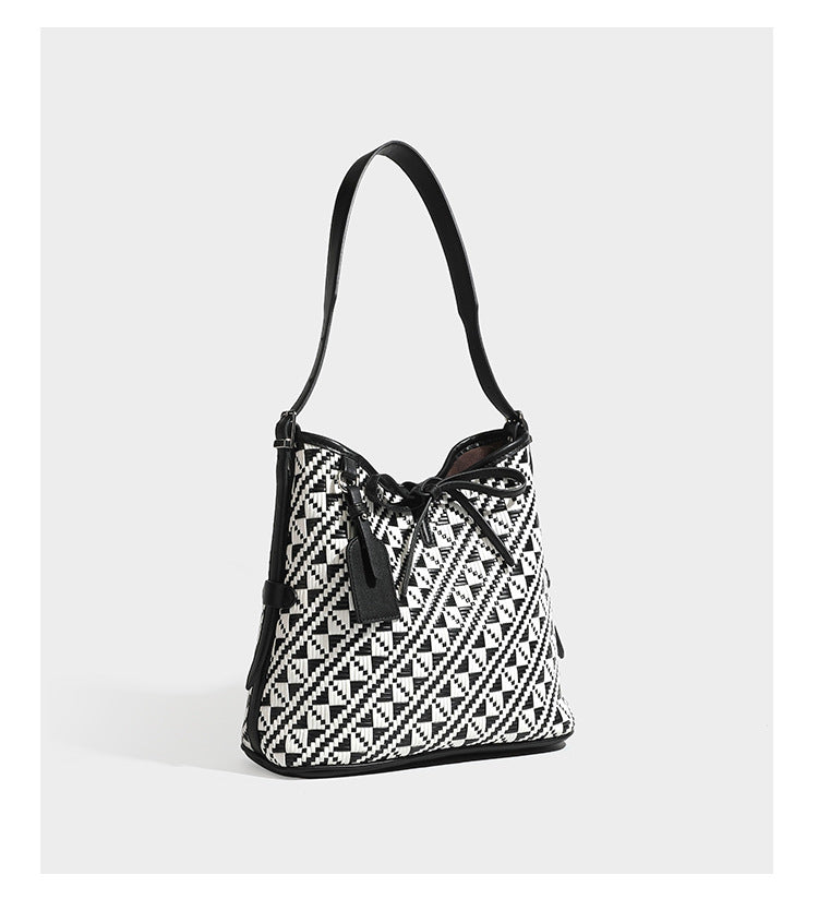 Woven geometric bucket shoulder bag in white and dark brown two-tone pattern with leather-look trim and drawstring top