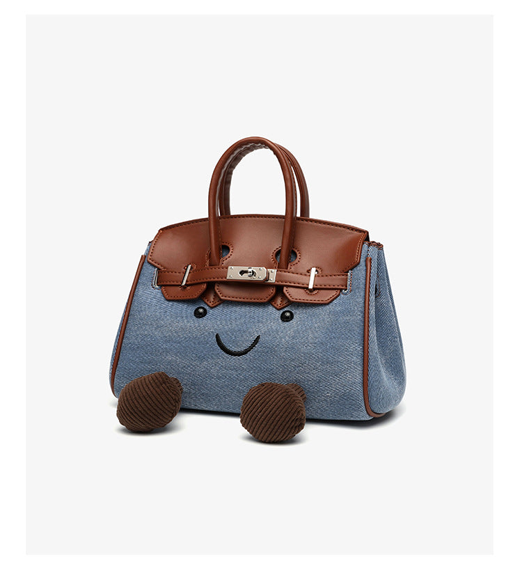 Small structured trapezoid satchel bag with smiling face motif, pom-pom accents, brown leather-look trim, silver-tone, detail
