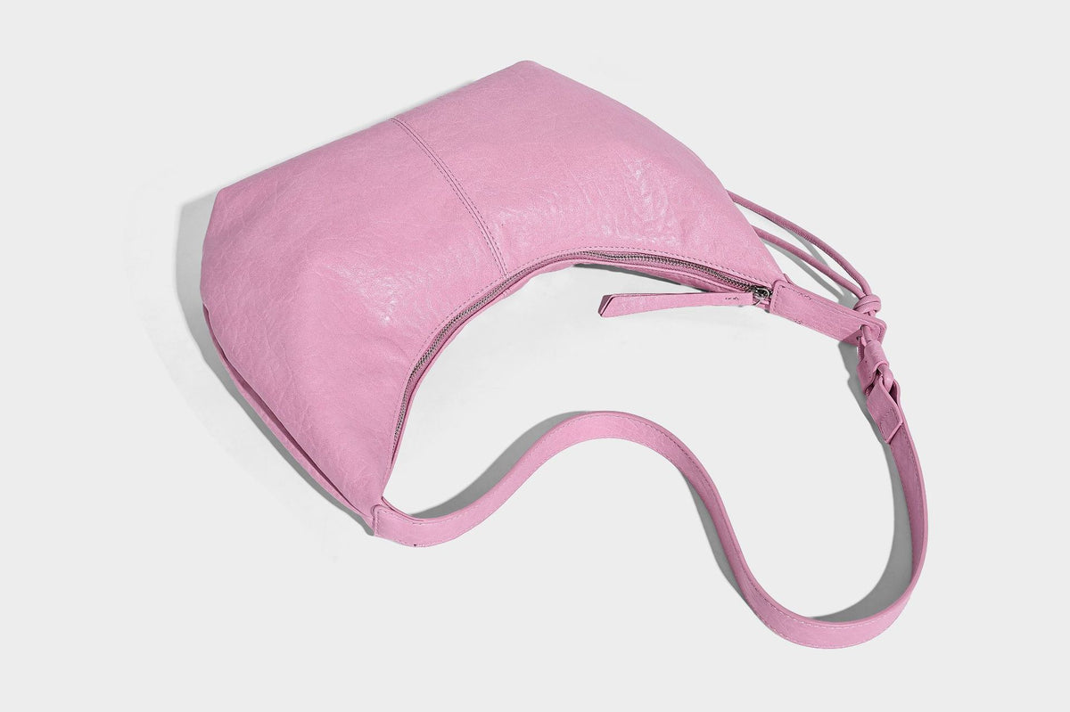 Slouchy crescent half-moon shoulder bag in pink pebbled textured finish with floral charm and knotted side detail, detail