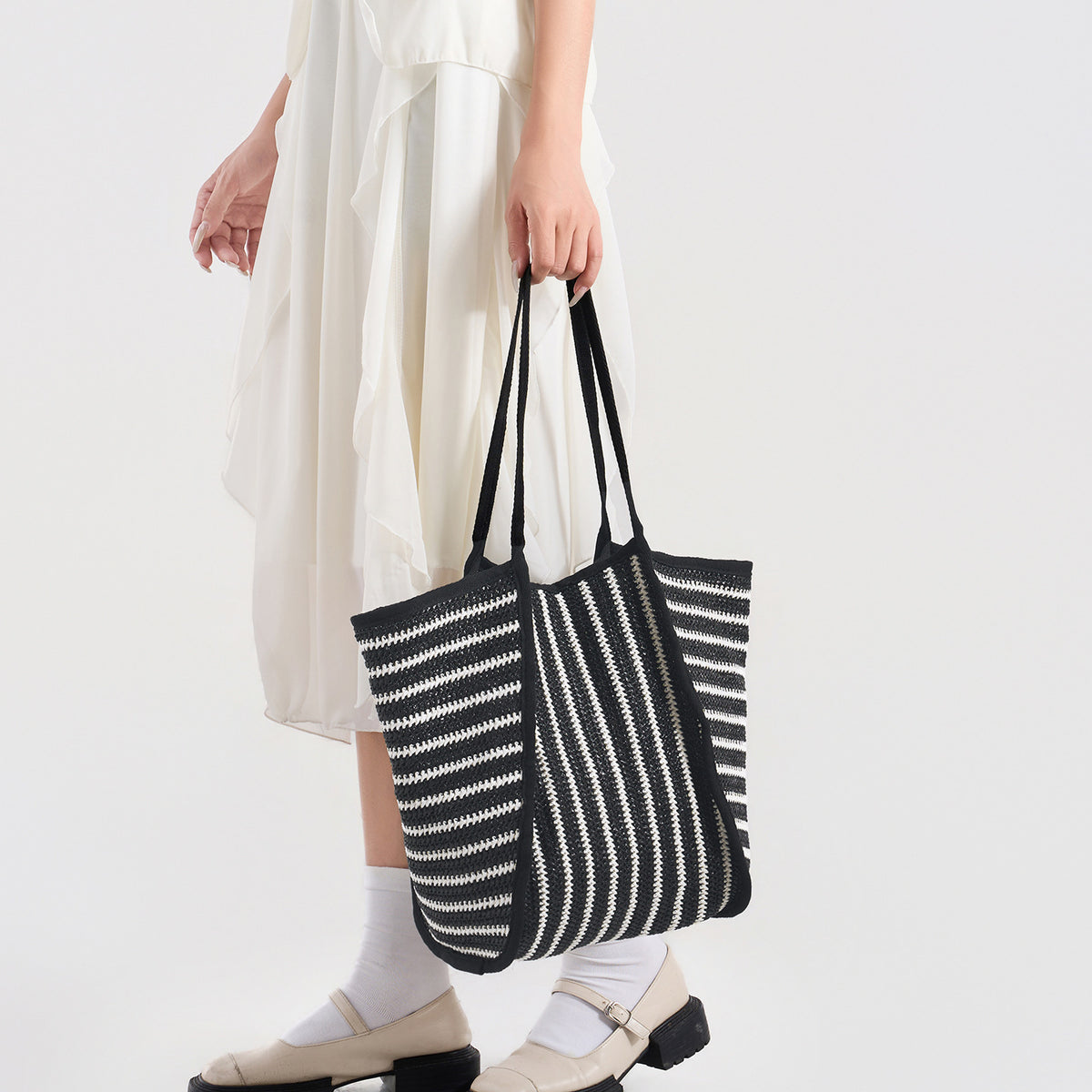 Large black-and-white striped woven tote bag with open top and long shoulder straps, detail view 2