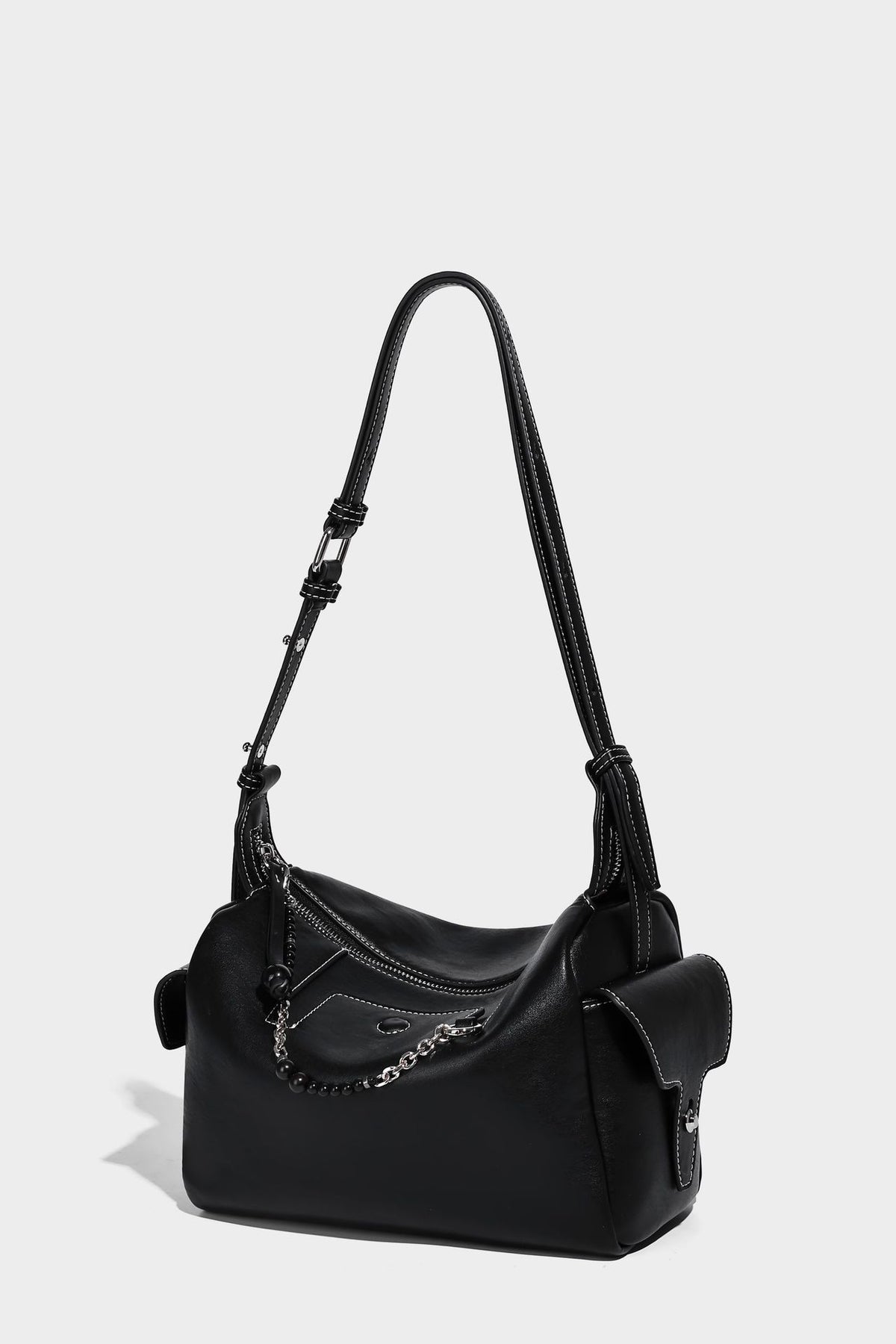 Small slouchy moto-style crossbody bag in smooth matte leather-look finish with white contrast stitching, silver-tone, detail