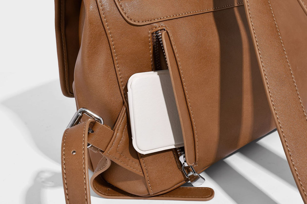 Structured tan leather-look flap backpack handbag with top handle, silver buckle hardware, and fold-over front closure