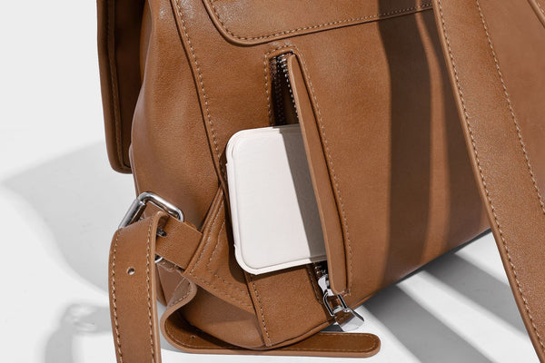 Structured tan leather-look flap backpack handbag with top handle, silver buckle hardware, and fold-over front closure