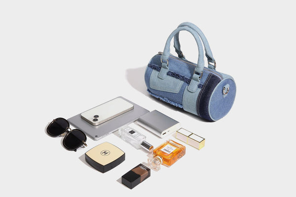 Mini barrel handbag in light and dark denim patchwork with frayed seam trim, dual top handles, top zip closure, and, detail