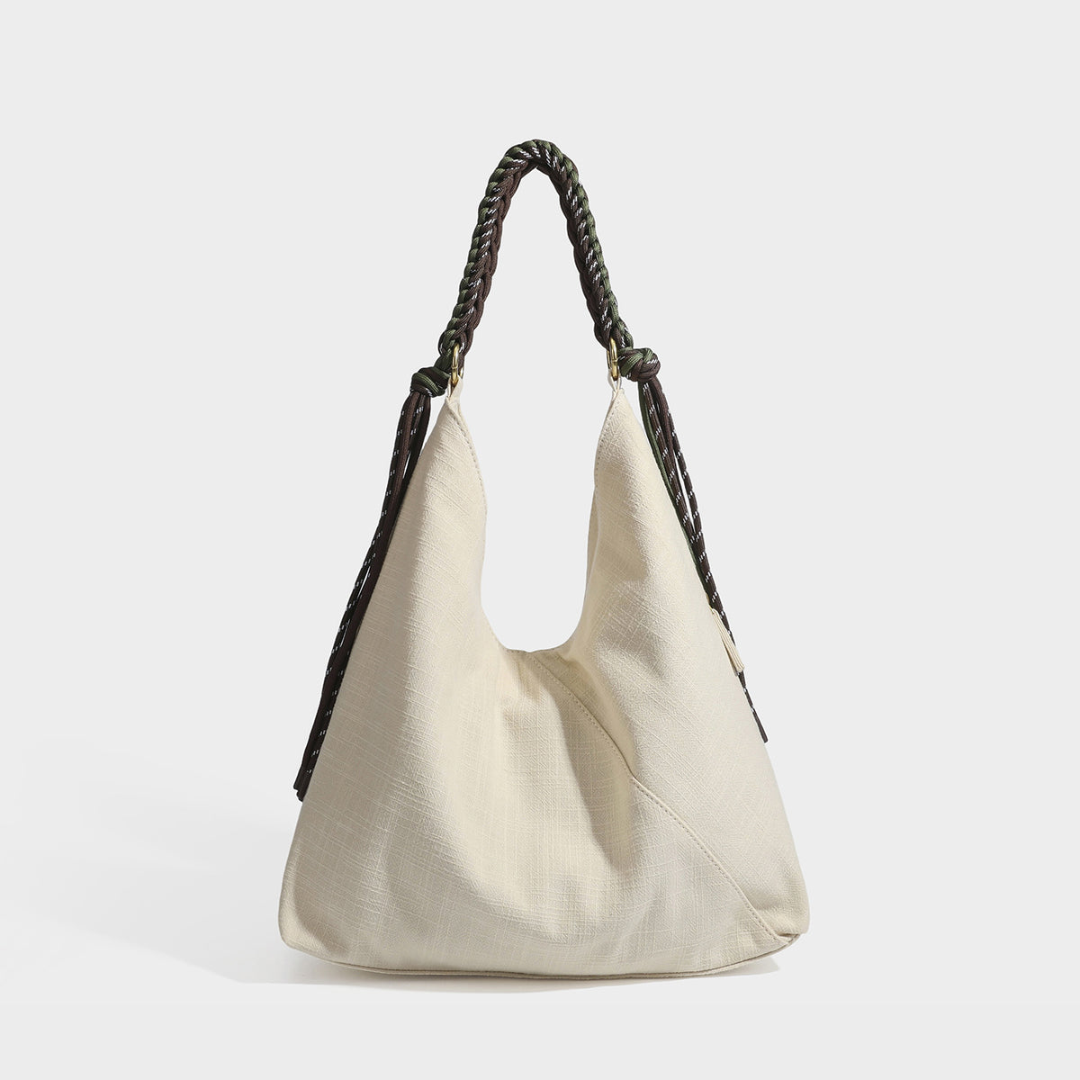 Soft slouchy cream canvas shoulder tote with braided brown and green cord handle, gold-tone ring hardware, and tassel trim