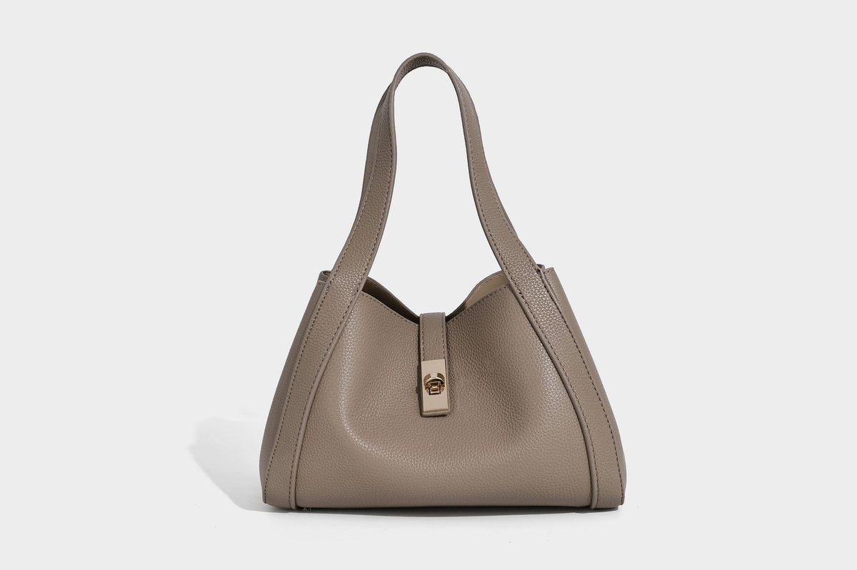 Structured trapezoid tote bag in taupe pebbled leather-look finish with gold-tone turn-lock hardware, dual top handles, and