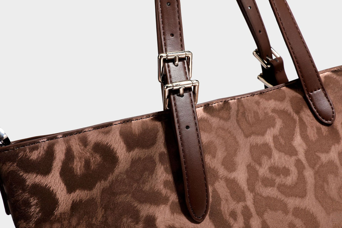 Glossy leopard-print tote bag with leather-look dark trim, dual top handles, detachable shoulder strap, and attached front