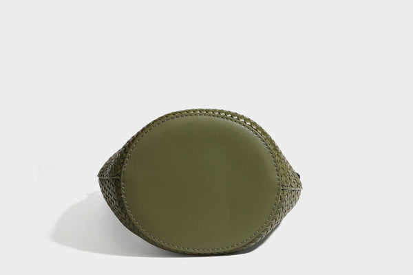 Olive green woven leather-look bucket bag with braided crossbody strap, knotted adjustment, and gold-tone tassel charm with