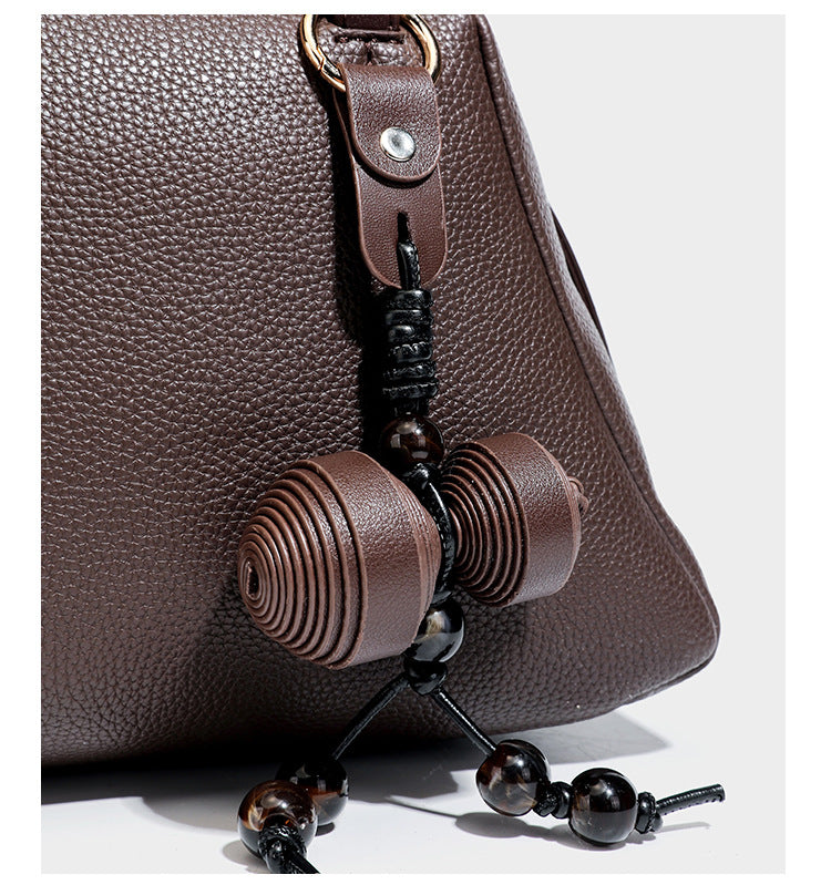 Structured trapezoid shoulder bag in dark brown pebbled leather-look finish with slim double straps, top zip closure, side
