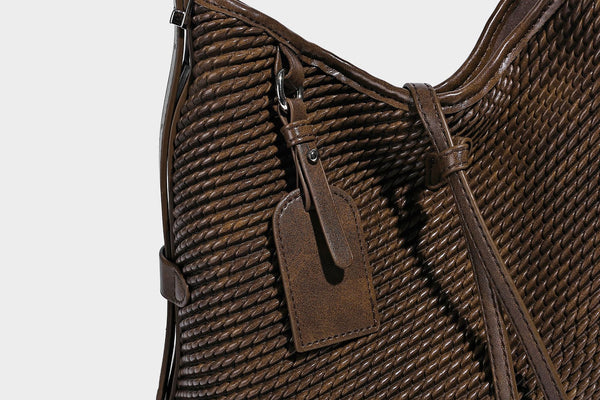 Große Schultertasche in Beutelform mit Flechtoptik, glatten Besätzen in Lederoptik, verstellbarem Riemen und hängendem Anhänger-Detail, Detailansicht