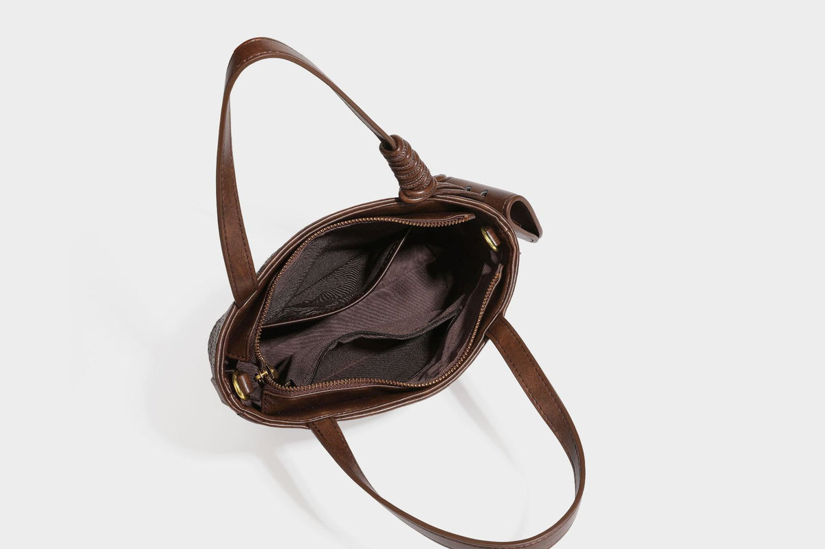 Strukturierte Tote Bag mit gewebter Oberfläche in Braun, goldfarbenen Metalldetails, seilumwickelten Tragegriffen, einer kleinen Fronttasche und weiteren Details
