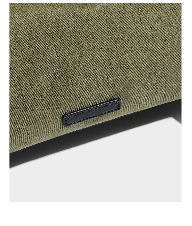 Olivgrüne Schultertasche in Zylinderform aus Canvas mit Riemen in schwarzer Lederoptik, Reißverschluss oben und silberfarbenen Beschlägen, Detailansicht