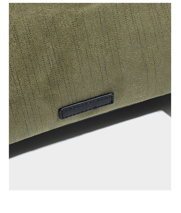 Olivgrüne Schultertasche in Zylinderform aus Canvas mit Riemen in schwarzer Lederoptik, Reißverschluss oben und silberfarbenen Beschlägen, Detailansicht