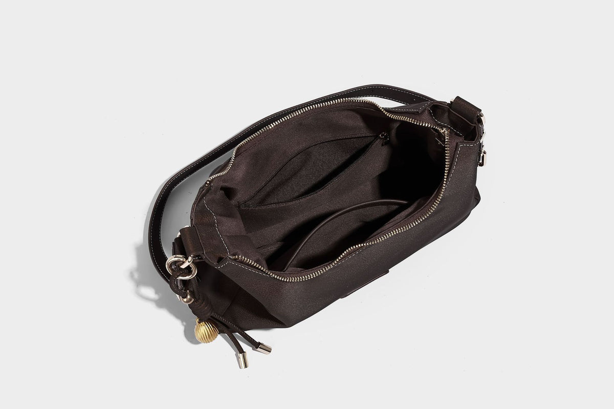 Crescent hobo shoulder bag in pebbled leather-look finish with top zipper, adjustable strap, gold-tone ring hardware, and