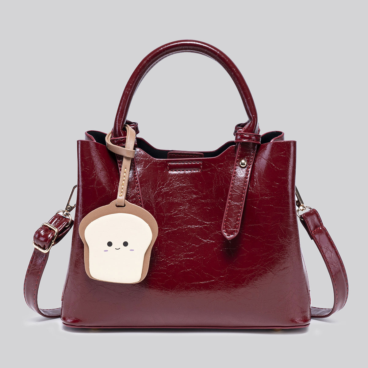 Structured glossy crinkled tote bag in burgundy red with gold-tone hardware, top handles, detachable shoulder strap, and