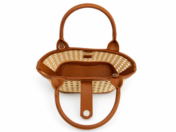 Structured mini tote bag with open-weave rattan body, leather-look arched handles and trim, front tab turn-lock closure, and