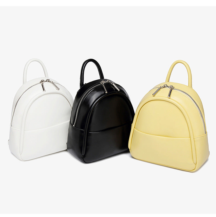 Kleine kuppelförmige Mini-Rucksackhandtasche in Pastellgelb mit glatter Lederoptik, oberem Bogenreißverschluss und silberfarbenen Details, Detailansicht
