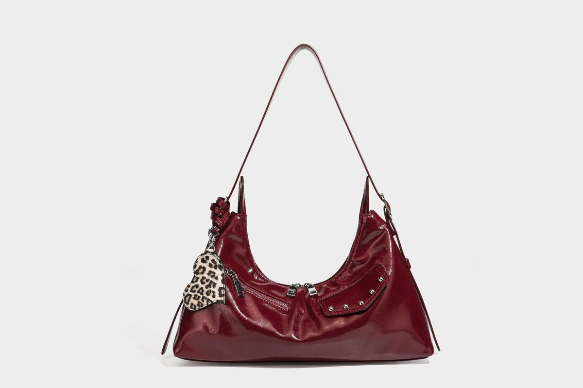 Glossy dark brown hobo shoulder bag with slim strap, front zip pocket, stud detail, and detachable leopard-print heart charm