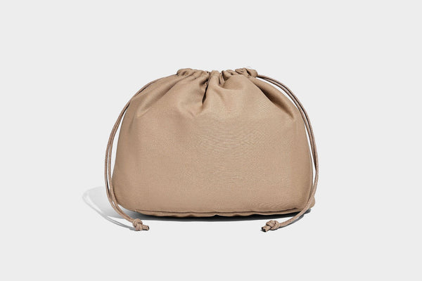 Two-tone beige and cream woven straw hobo shoulder bag with brown leather-look trim, long shoulder strap, and tassel-bead