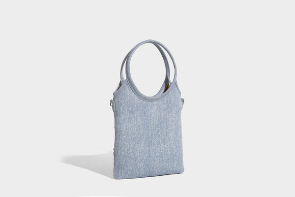 Kleine hellblaue Mini-Tote-Bag aus Stoff mit weißer Perlenblumenverzierung, runden Henkeln, silberfarbenen Beschlägen und