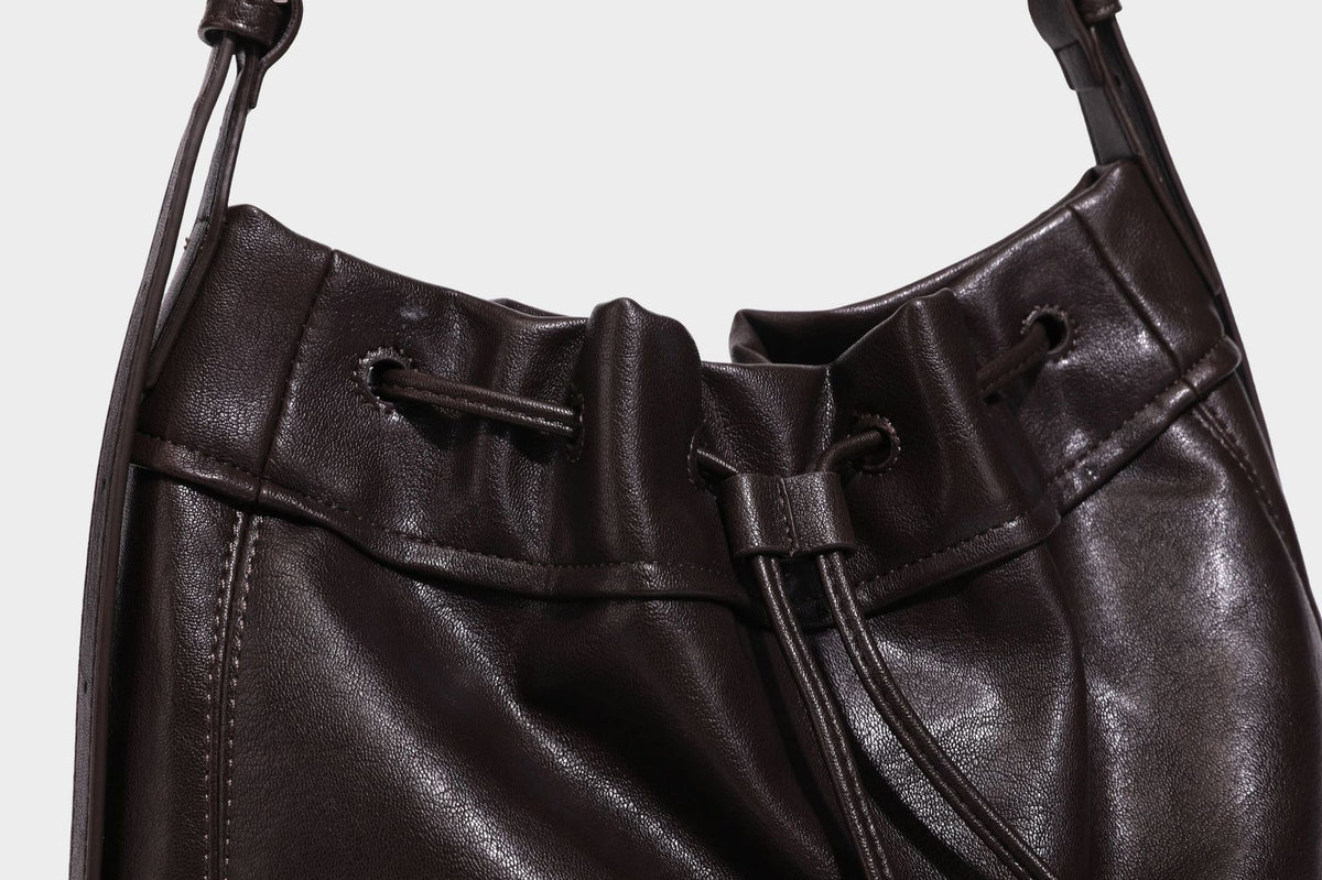 Lässig fallende Beuteltasche mit Kordelzug in dunkler Espresso-Lederoptik, verstellbarem Riemen und Ringbeschlägen aus Metall