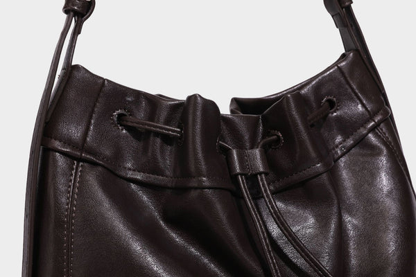 Lässig fallende Beuteltasche mit Kordelzug in dunkler Espresso-Lederoptik, verstellbarem Riemen und Ringbeschlägen aus Metall