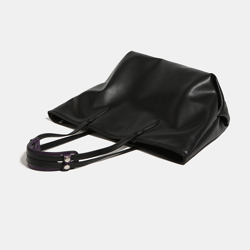 Large black leather-look trapezoid tote bag with double shoulder straps and purple accent hardware, detail view 4