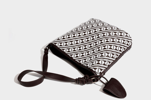 Geflochtene Schultertasche mit geometrischem Ethno-Muster, Besatz in dunkelbrauner Lederoptik, langem verstellbarem Träger und kleinem hängendem Reißverschluss