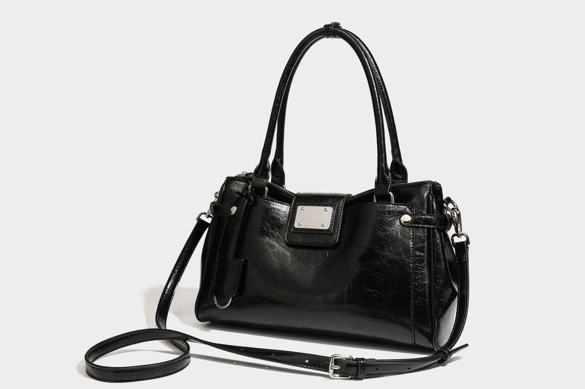 Structured glossy crinkled leather-look satchel with double top handles, front metal-plaque tab, silver-tone hardware, and