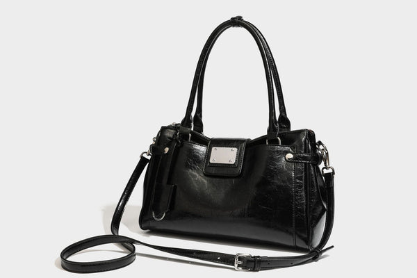 Structured glossy crinkled leather-look satchel with double top handles, front metal-plaque tab, silver-tone hardware, and