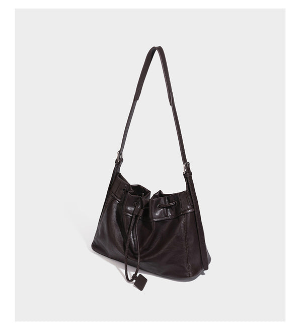 Slouchy drawstring bucket bag in dark brown leather-look finish with long adjustable shoulder strap and gathered tie closure