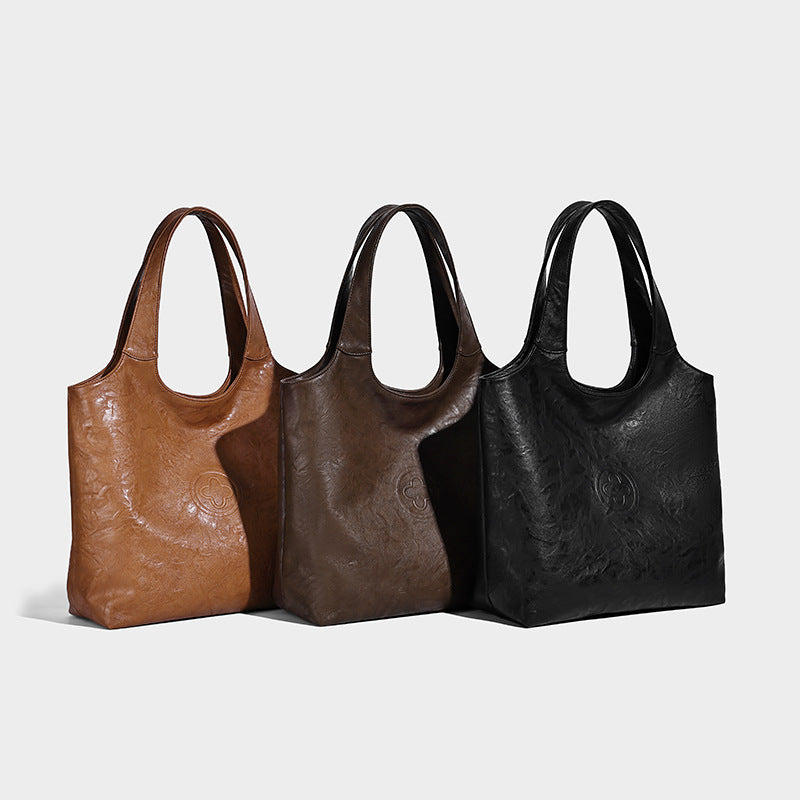 Large open-top tote bag with crinkled leather-look finish, long double shoulder straps, and embossed circular detail on