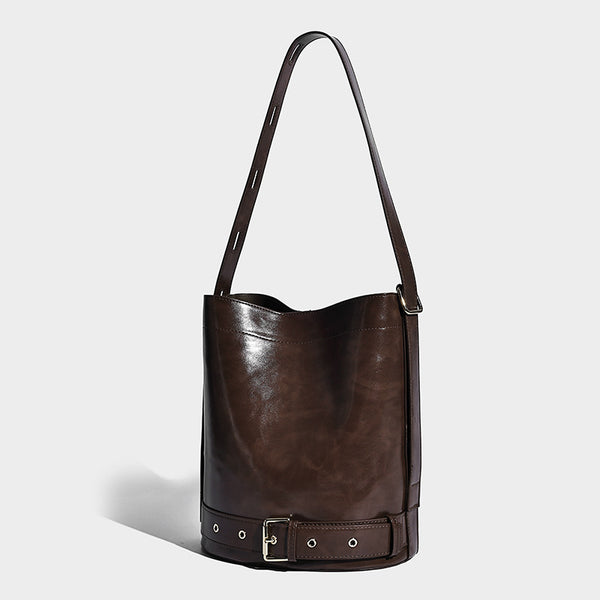 Glänzende Bucket-Bag in Lederoptik mit umlaufendem Riemen, silberfarbenen Ösen und verstellbarem Schulterriemen, Vorderansicht