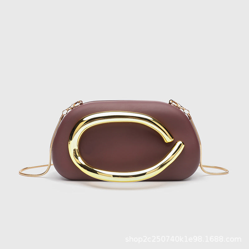 Kleine rechteckige Crossbody-Clutch mit abgerundeten Ecken, oversized poliertem C-förmigem Goldgriff und schmalem Goldkettenriemen, Detailansicht