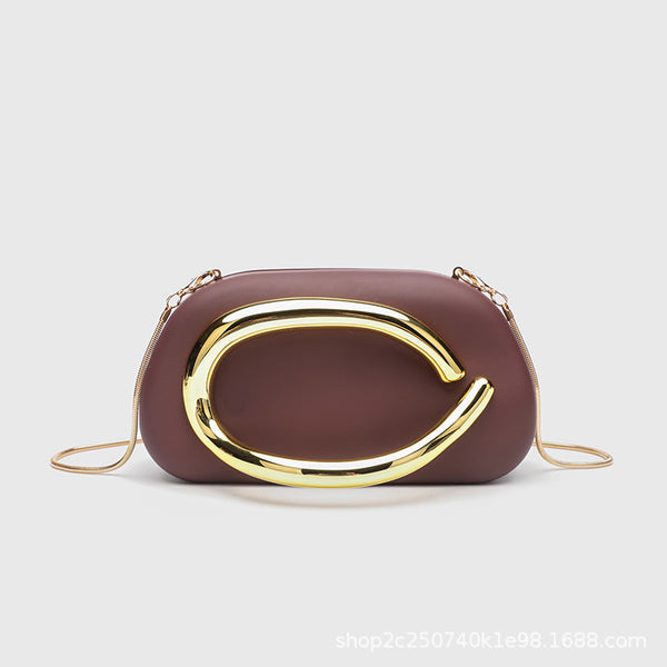 Kleine rechteckige Crossbody-Clutch mit abgerundeten Ecken, oversized poliertem C-förmigem Goldgriff und schmalem Goldkettenriemen, Detailansicht