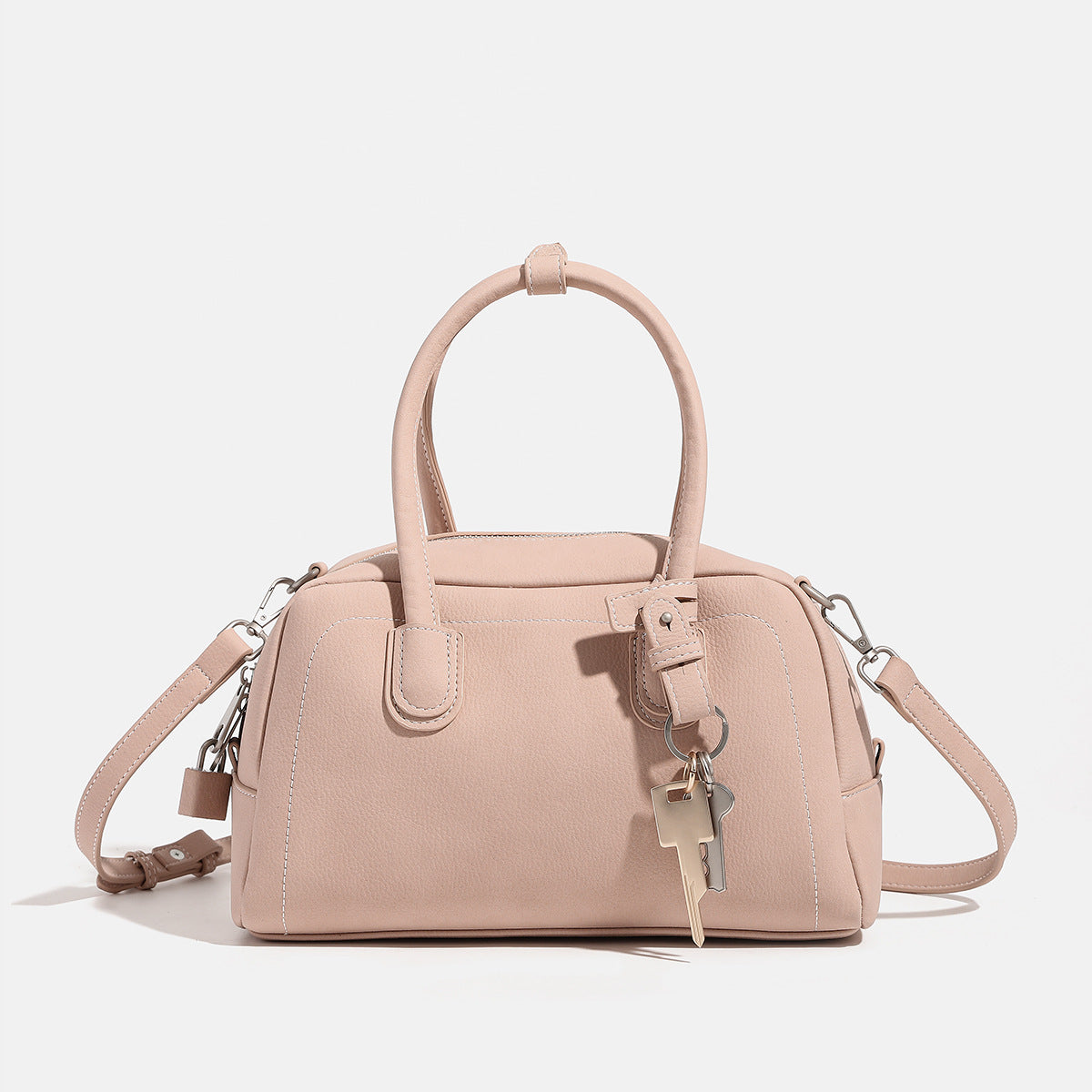 Kompakte, strukturierte Henkeltasche mit matter genarbter Oberfläche, geknoteten Doppelgriffen, goldenem Schlüsselanhänger und abnehmbarem, Detailansicht
