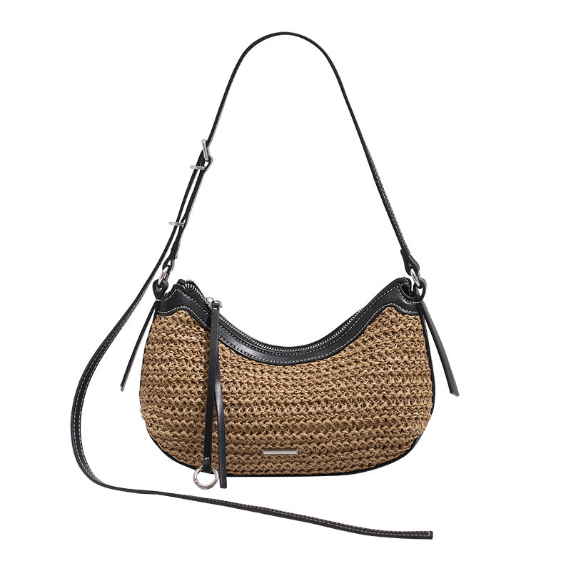 Tan woven straw half-moon shoulder bag with black leather-look trim, zip closure, tassel pull, and adjustable crossbody