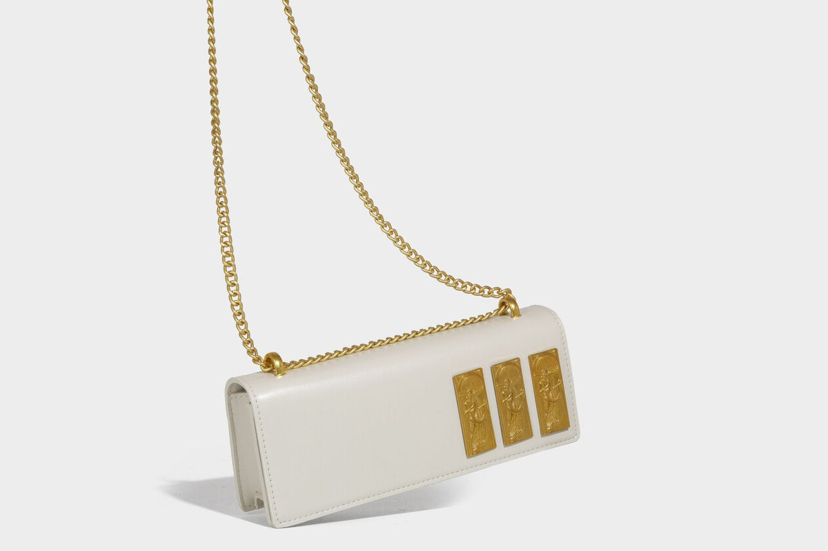 Structured rectangular crossbody bag with glossy finish, three vertical gold-tone embossed plaques, and gold chain strap