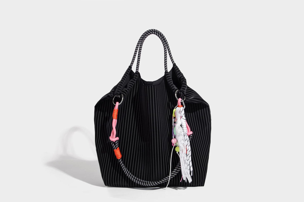 Slouchy pinstripe tote bag with braided rope handles, metal ring hardware, and colorful knotted rope charm, detail view 33